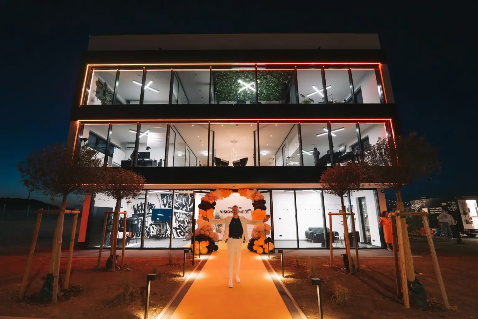 Beleuchteter Eingang des VISION CAMPUS bei Nacht